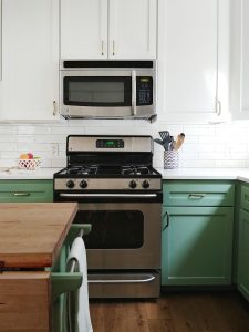 Front of green and white painted kitchen cabinets in BM 445 Greenwich Village and SW 7008 Alabaster by Paper Moon Painting, Austin Hyde Park