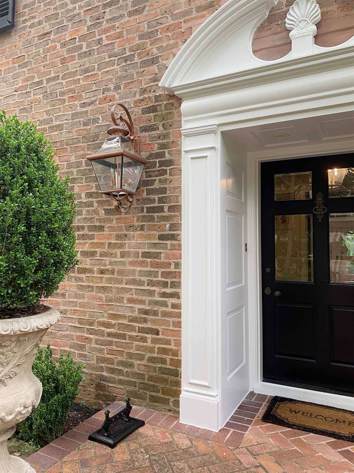 Angled entry of brick Alamo Heights exterior, shutter in Sherwin Williams Tricorn Black, trim in Benjamin Moore Pure White, TX home painter
